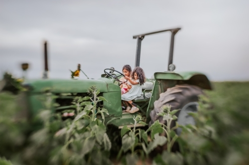 Two little girls on a green tractor
