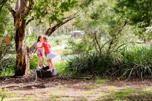 Image of Happy kid playing in backyard on tyre swing - Austockphoto