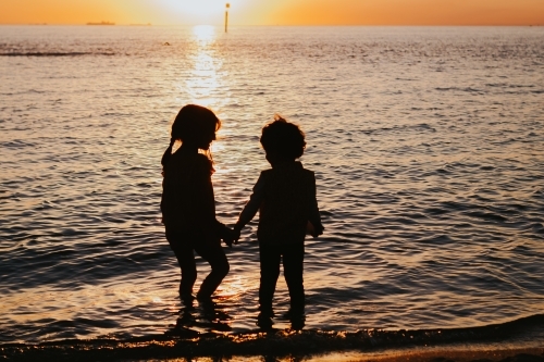 Two little girls silhouette at the beach - Australian Stock Image
