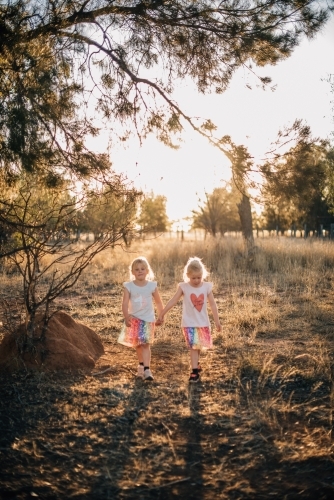 Two little girls walking through farmland, holding hands