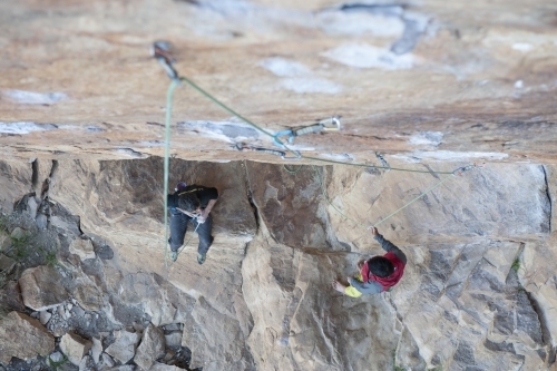 Two male rock climbers below route