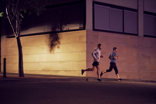 Two men fitness training in urban city at night - Australian Stock Image