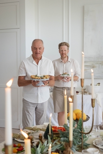 Two men holdig platters of Christmas food - Australian Stock Image