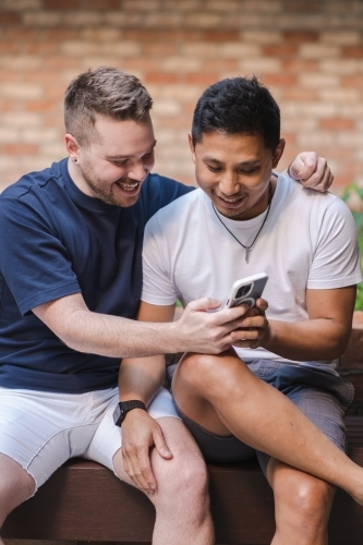 two men looking at phone screen - Australian Stock Image