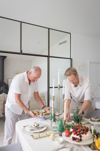 Two men setting up Christmas table together - Australian Stock Image