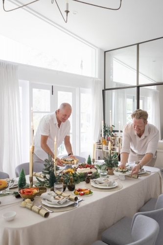 Two men setting up Christmas table together - Australian Stock Image