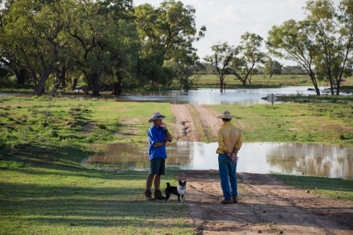 Two men talking near a flooded creek - Australian Stock Image