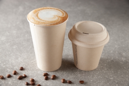 Two paper coffee cup sizes on table full of warm beverage - Australian Stock Image