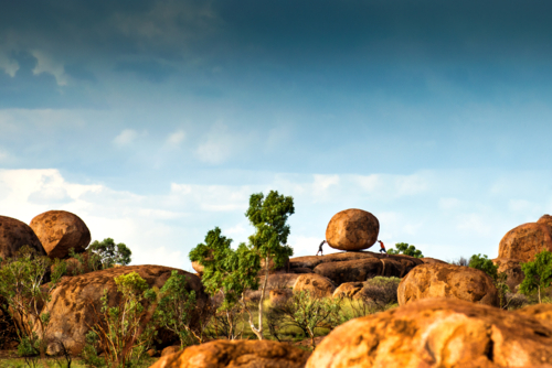 Two people appear to push a giant boulder among the rounded rocks of the outback. - Australian Stock Image