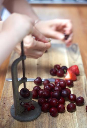 Two people pitting cherries for a cake
