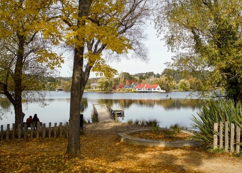 Two people sitting on the bench by the lake - Australian Stock Image