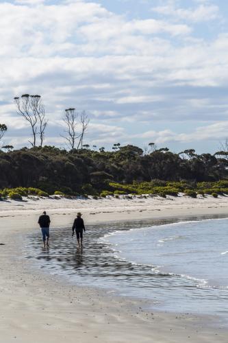 Two people strolling along the beach - Australian Stock Image