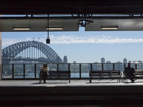Two people waiting at Circular Quay Railway Station with the Harbour Bridge in the background - Australian Stock Image