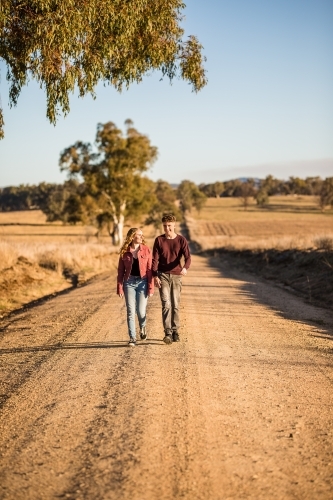 Two people walking down dirt road in afternoon - Australian Stock Image