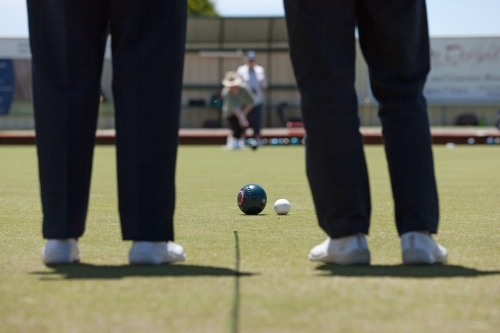 Two people watching another person bowling