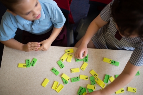 Two primary school girl students collaborating with coloured word tiles - Australian Stock Image