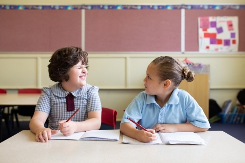 Two primary school girl students in a classroom looking at each other - Australian Stock Image