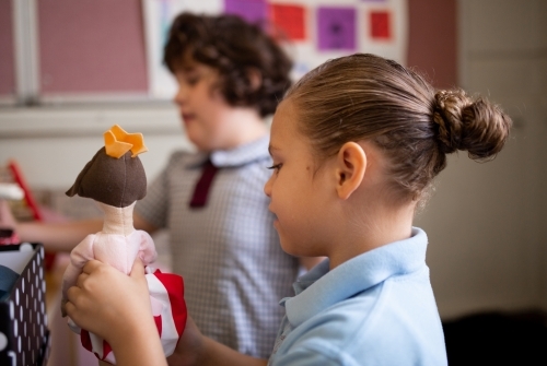 Two primary school girl students playing with a hand-made doll - Australian Stock Image