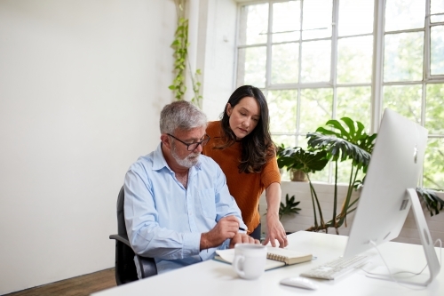 Two professional business people, sharing ideas in an open-plan studio office - Australian Stock Image