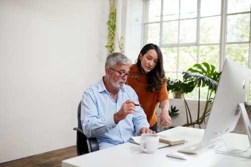 Two professional business people, sharing ideas in an open-plan studio office - Australian Stock Image