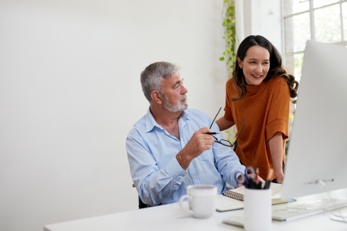 Two professional business people, sharing ideas in an open-plan studio office - Australian Stock Image