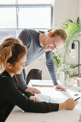 Two professionals working in a studio discussing a floor plan - Australian Stock Image