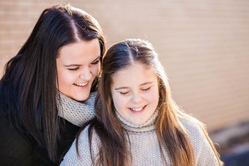 Two sisters looking down laughing together - Australian Stock Image