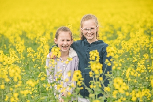 Two sisters standing in their family canola field - Australian Stock Image