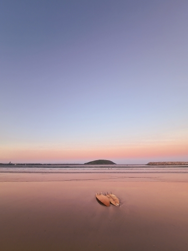 Two surfboards on the sand as the sun sets near the beach - Australian Stock Image