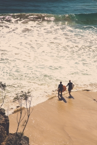 Two surfers walking the beach