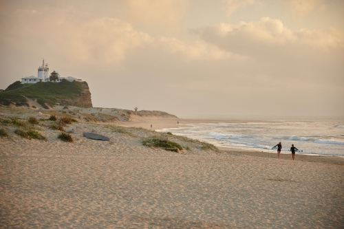 Two surfers walking to ocean at sunset - Australian Stock Image