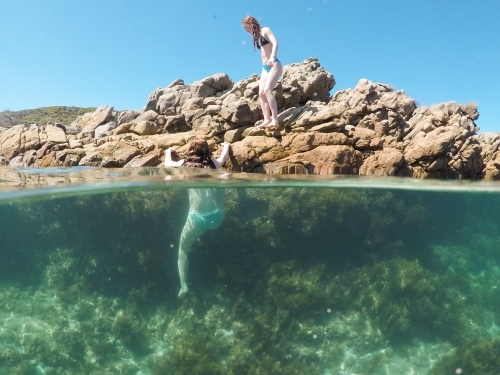 Two teenage girls playing in an ocean rock pool - Australian Stock Image