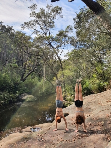 Two teenagers doing a handstand by a waterhole - Australian Stock Image