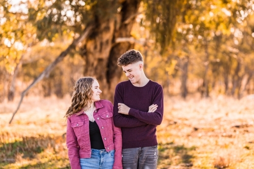 Two teens looking at each other pulling faces outside in golden hour - Australian Stock Image