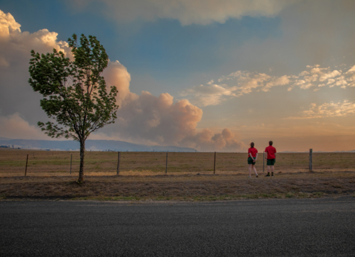 Two teens looking at the smoke of a bushfire in the distance - Australian Stock Image