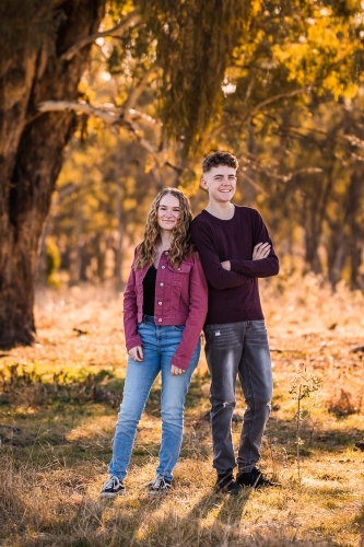 Two teens standing leaning on each other smiling