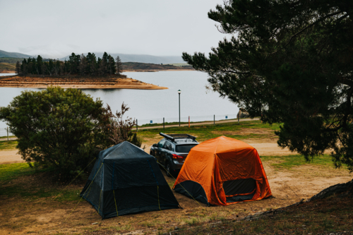 two tents on a camping site in front of a lake on a winter day - Australian Stock Image