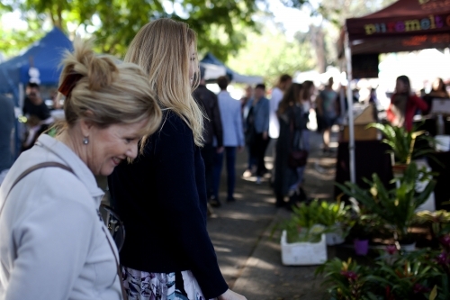 Two women walking through an outdoor market - Australian Stock Image