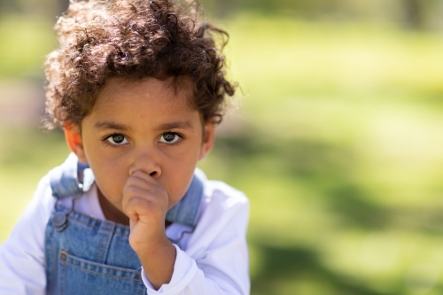 Two year old child sucking thumb outdoors - Australian Stock Image
