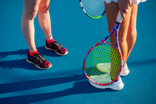 Two young female athletes stand on a blue tennis court ready to play, with racquets in hand - Australian Stock Image