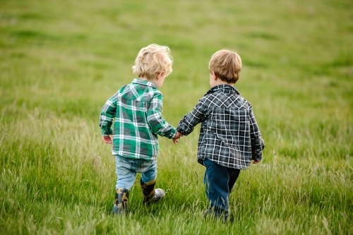 Two young friends walking across a green paddock
