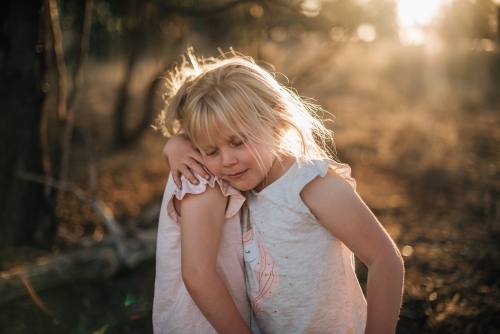 Two young girls hugging outside in last light - Australian Stock Image