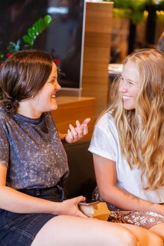 Two young women catching up and chatting in shopping mall - Australian Stock Image