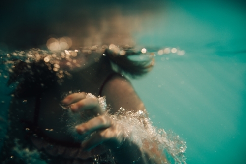 Underwater view of girls hand as she swims