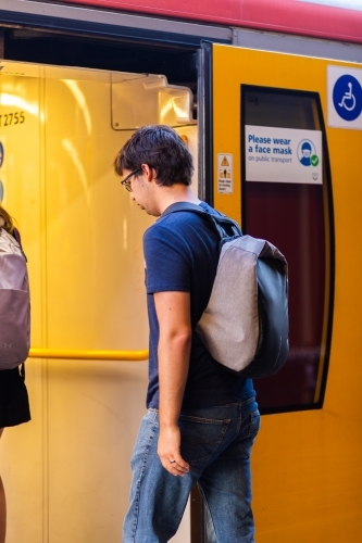 Uni student walking onto train to commute to uni campus - Australian Stock Image