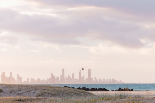 United States Army Blackhawk helicopter flying over Currumbin Beach towards Gold Coast city skyline - Australian Stock Image