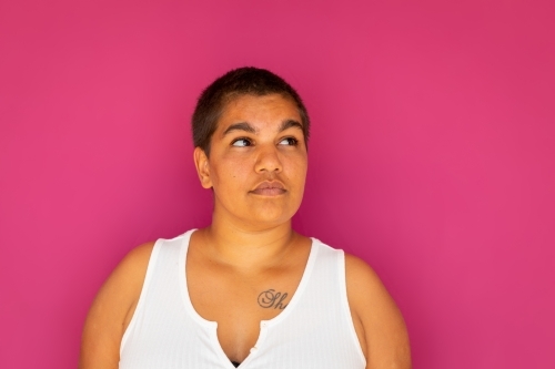 upper body of woman with very short hair against magenta backdrop - Australian Stock Image