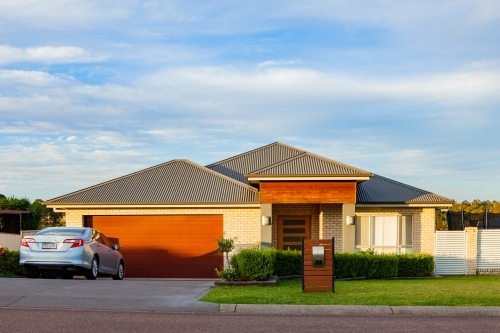 Urban house with car parked in driveway in the evening - Australian Stock Image