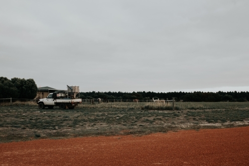 Ute parked near country home on farmland with red dirt road