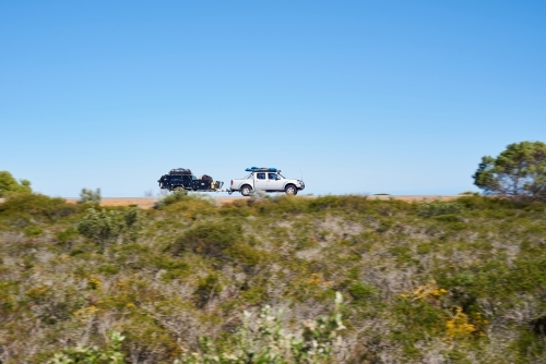 Ute towing a camper trailer on a road trip in coastal Western Australia, with motion blur. - Australian Stock Image